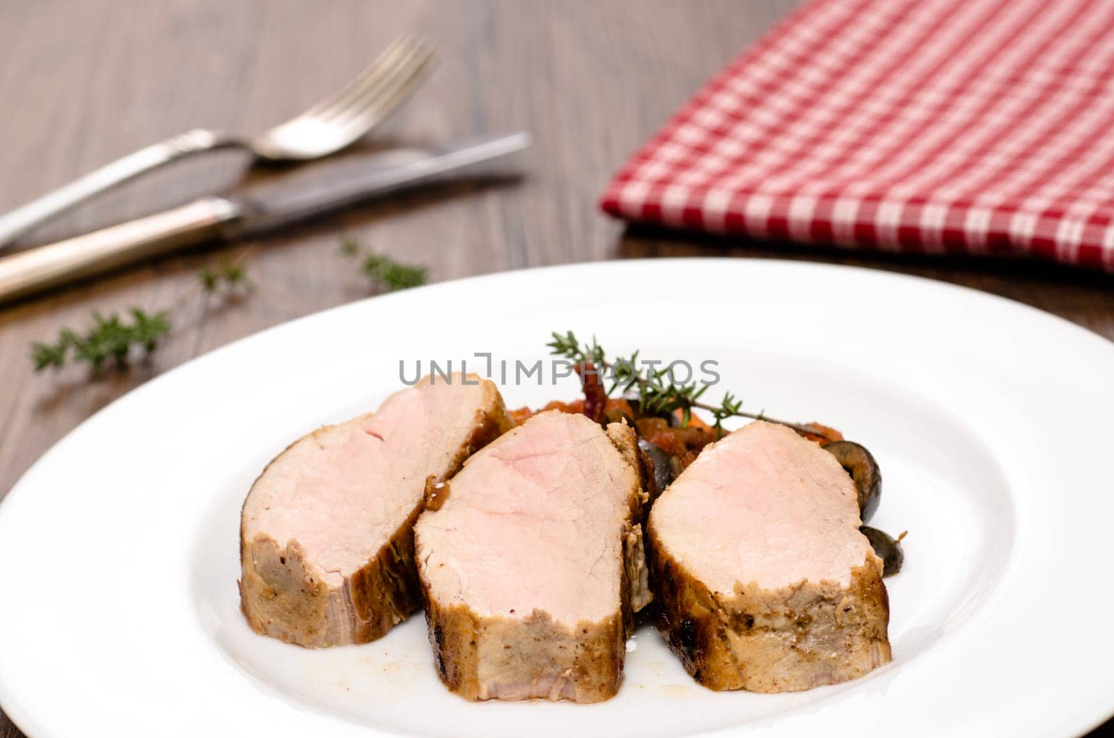 Three slices of roasted pork tenderloin on one plate