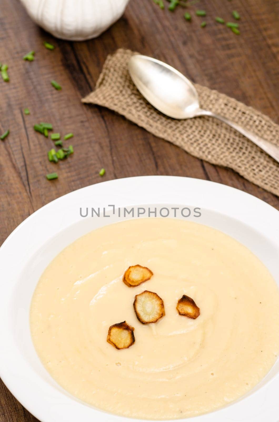 Parsnip cream soup with roasted parsnips on a white plate
