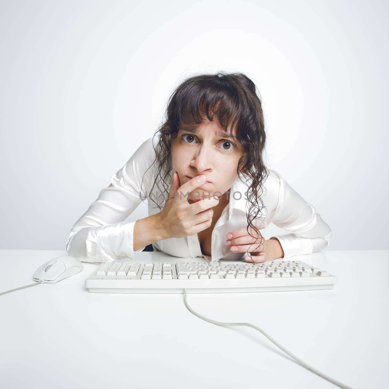 Funny and quite grotesque frontal portrait of a doubtful woman at her office desk