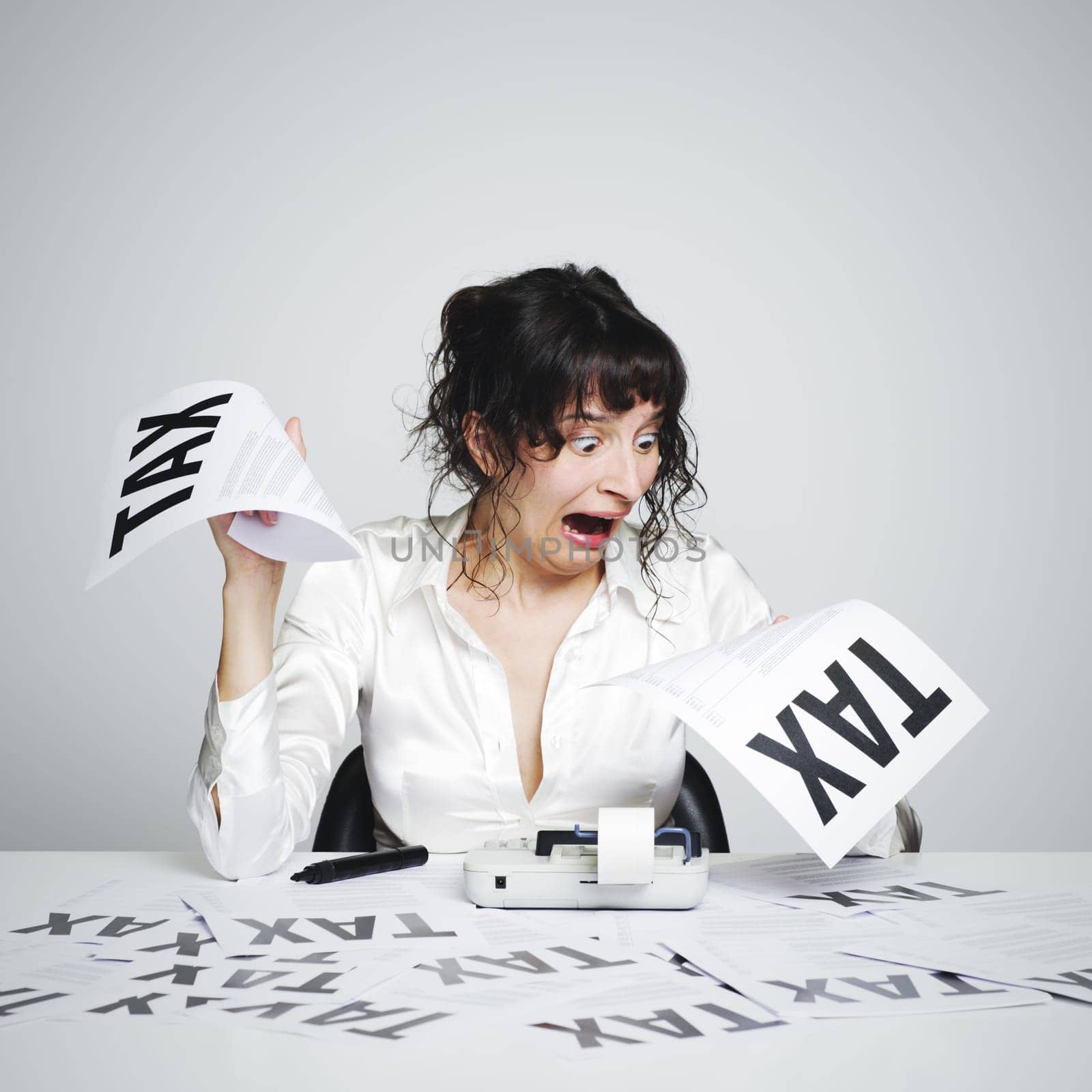 Very surprised  woman at her desk looking at terrible tax bills