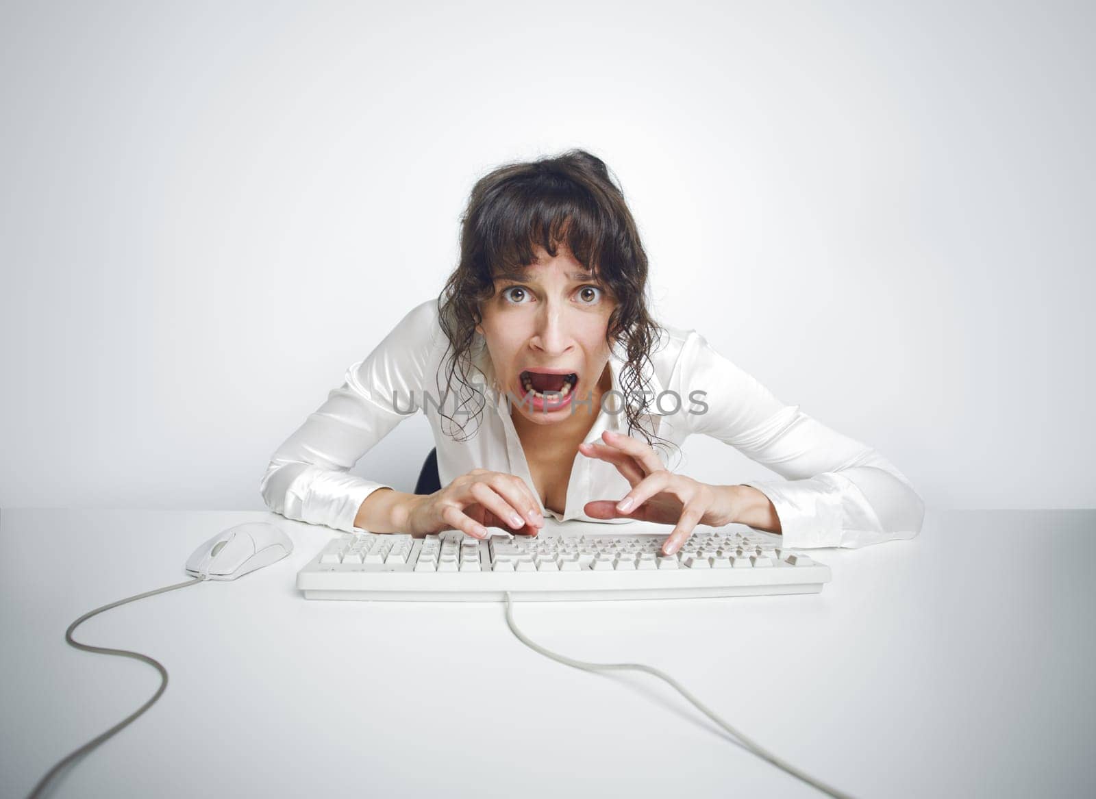 Funny and quite grotesque frontal portrait of a scared woman at her office desk
