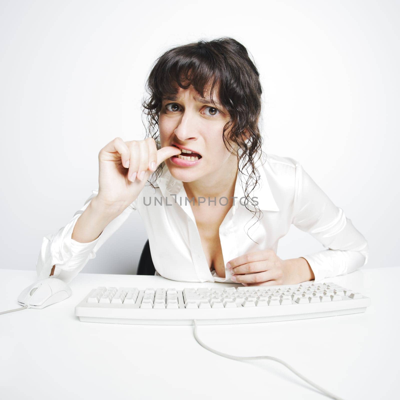 frontal portrait of a doubtful woman nail biting at her office desk