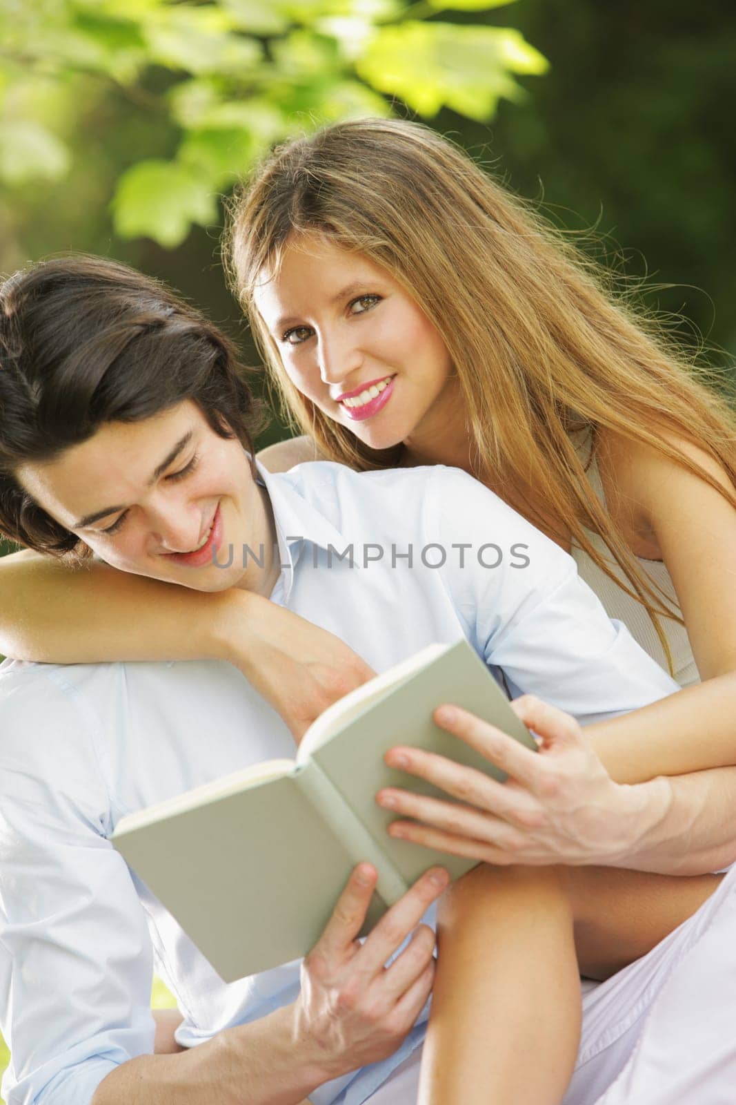 a young couple read a book together in the park. close up.