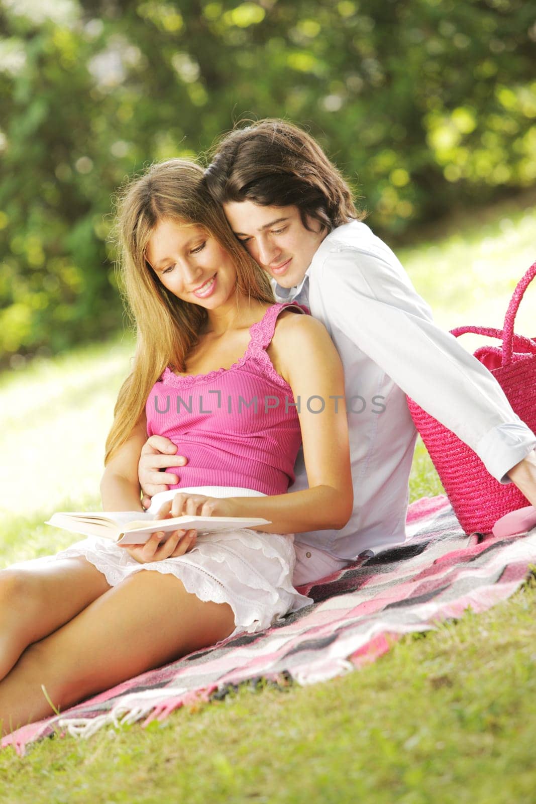 a young couple read a book together in the park