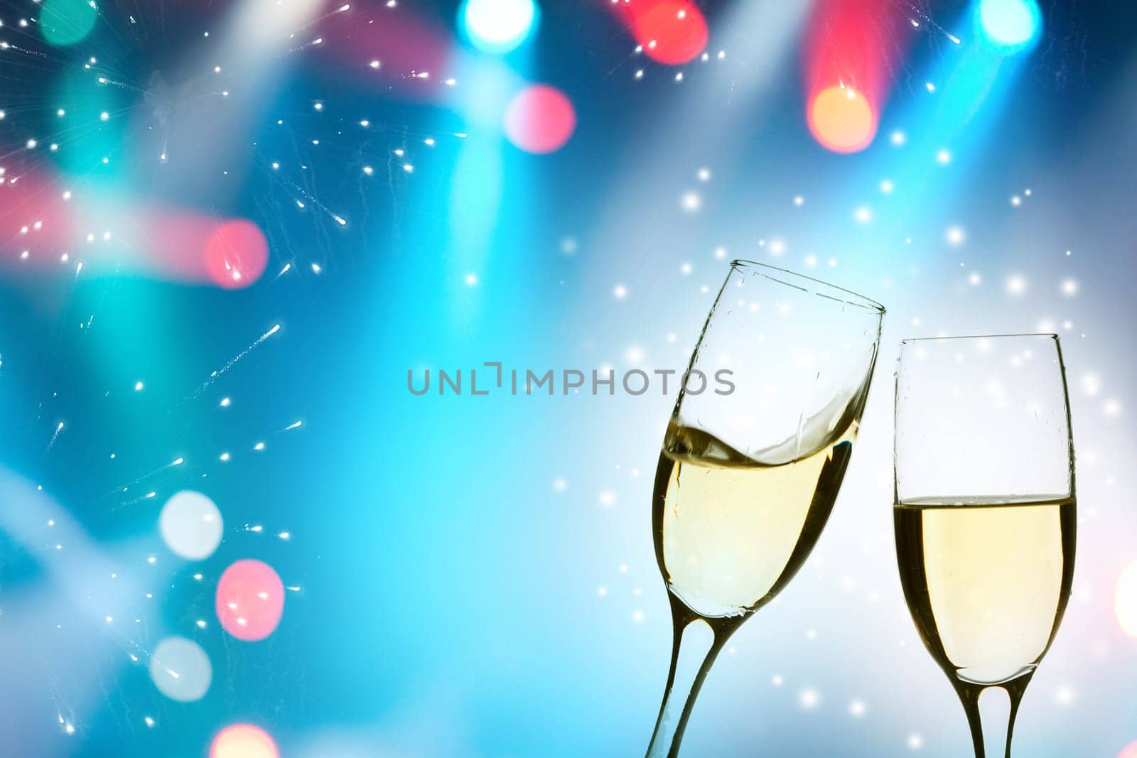 Two glasses of champagne with colorful lights in the background