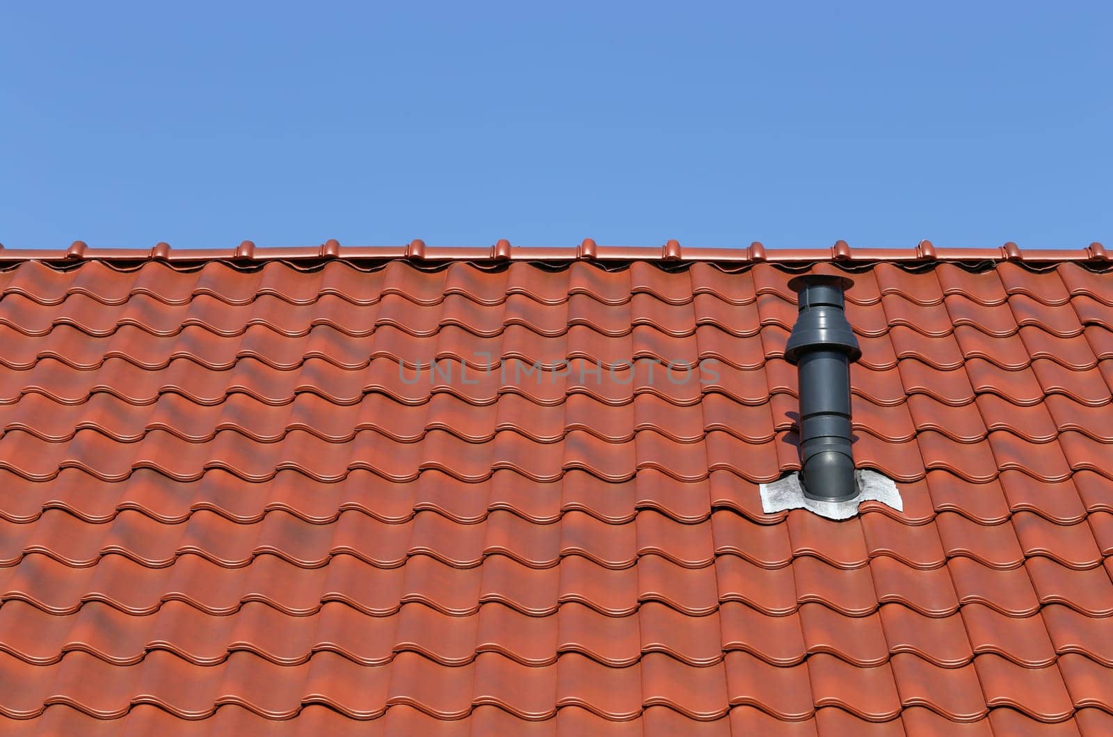 Red roof with chimney against a blue sky