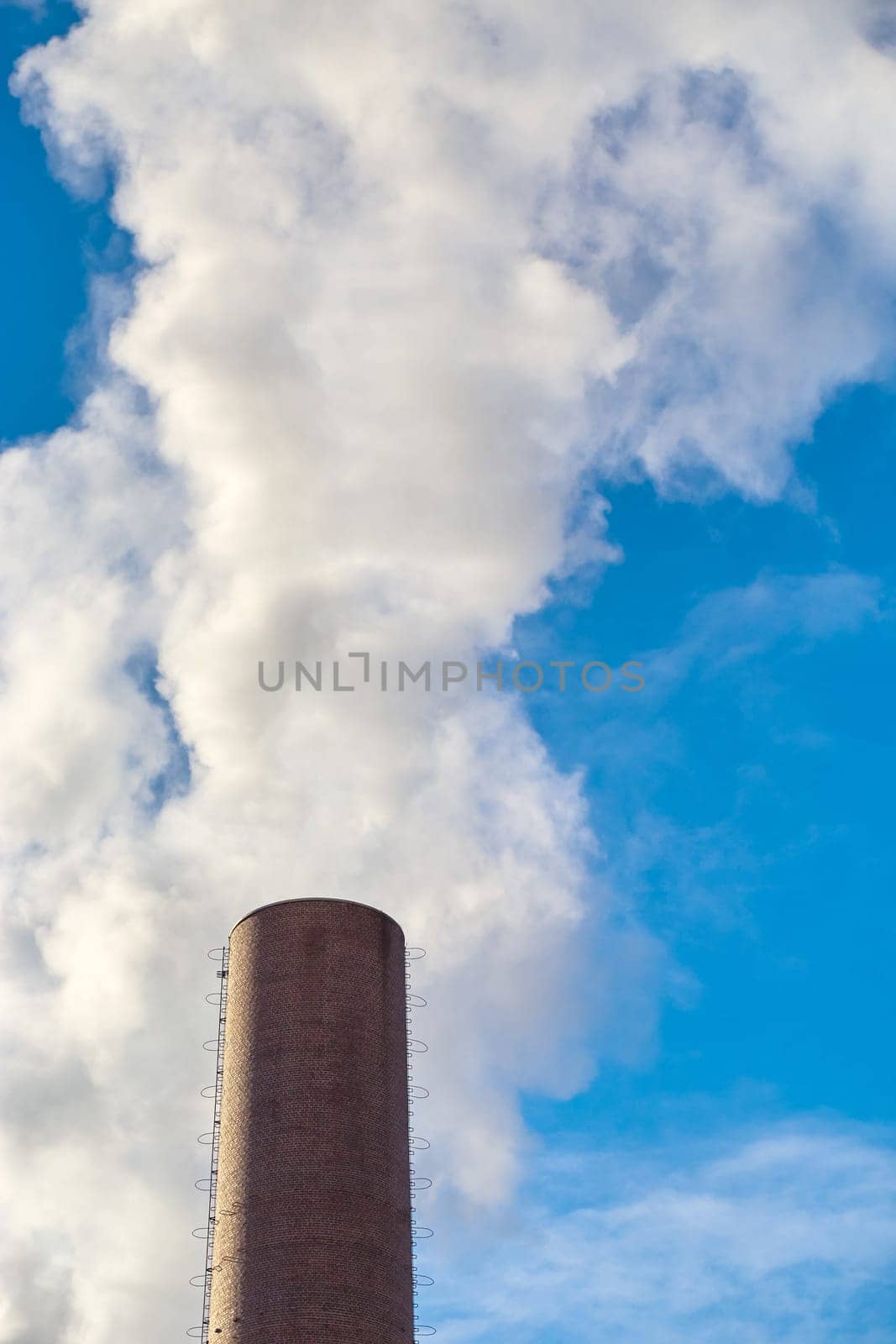 Chimney with smoke against a blue sky