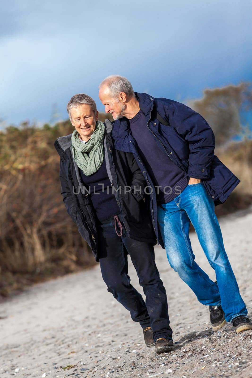 Older adult happy couple walking on the beach in autumn lifestyle happiness