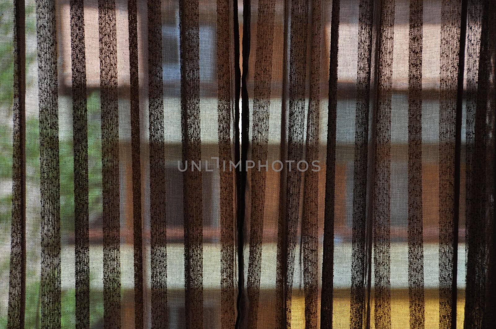 Brown transparent curtains and distorted colorful building in the background.