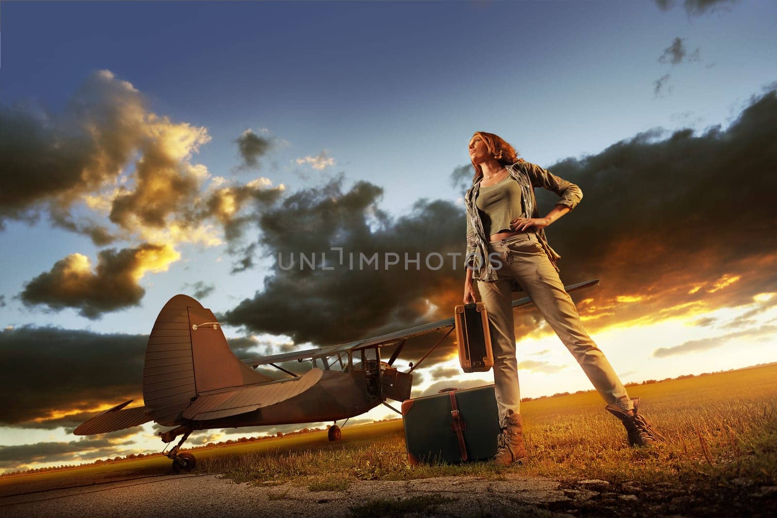Fashion young womanl with a suitcase. Airplane in the background.