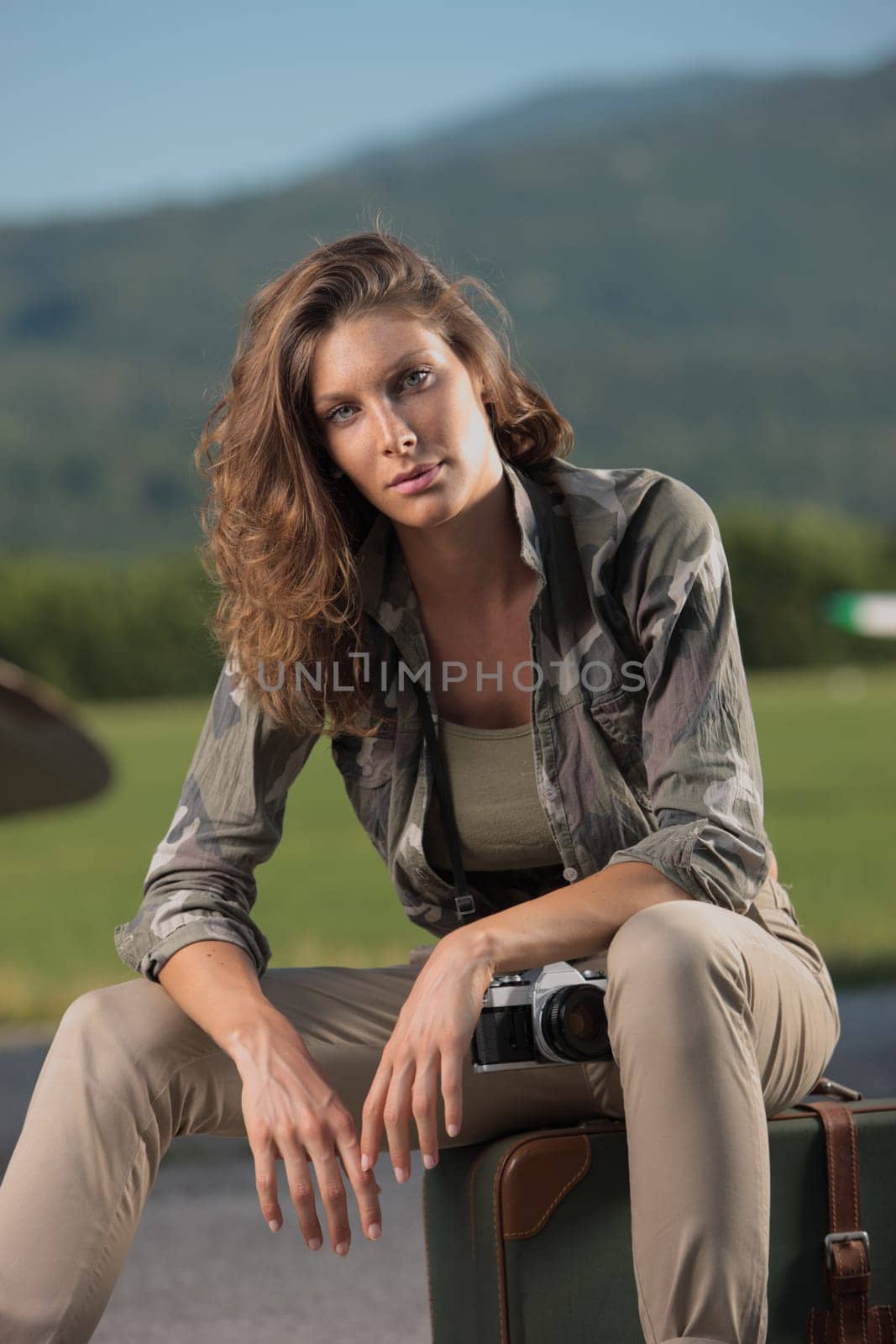 Portrait of young fashion woman with old camera and vintage suitcase