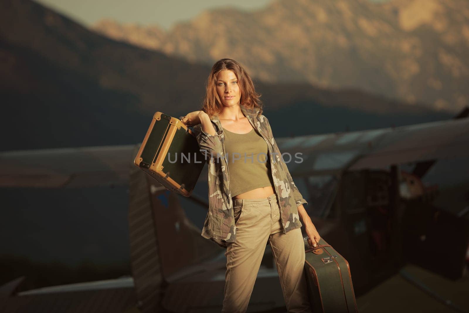 Young beautiful woman with suitcases ready to go by plane at sunset