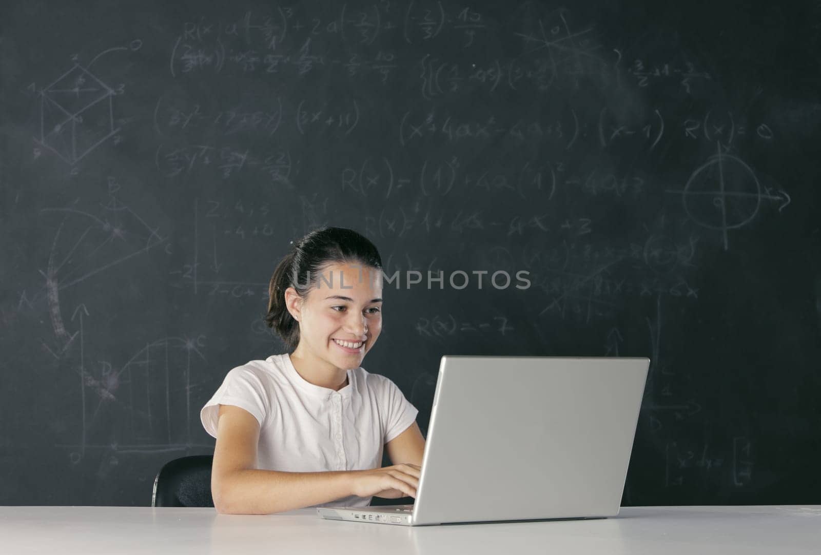 Young girl with laptop, blackboard on background