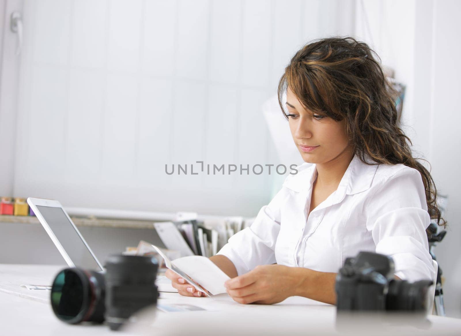 Female photographer examines the pictures, is sitting at her desk in the office