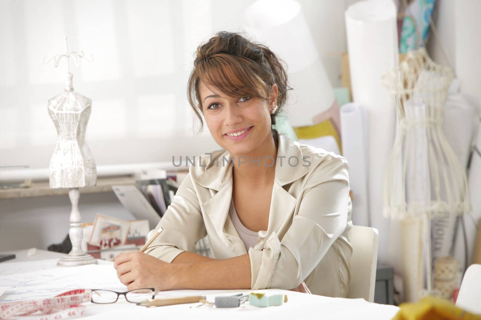 Smiling female fashion designer sitting at office desk