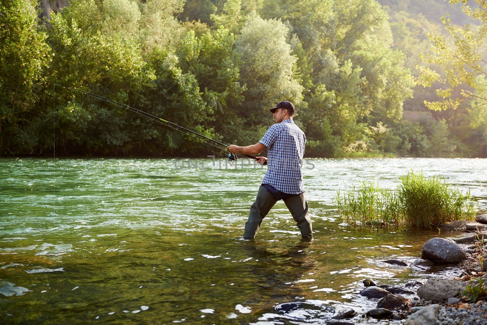 mid adult man on holidays on river, relaxing and fishing trout