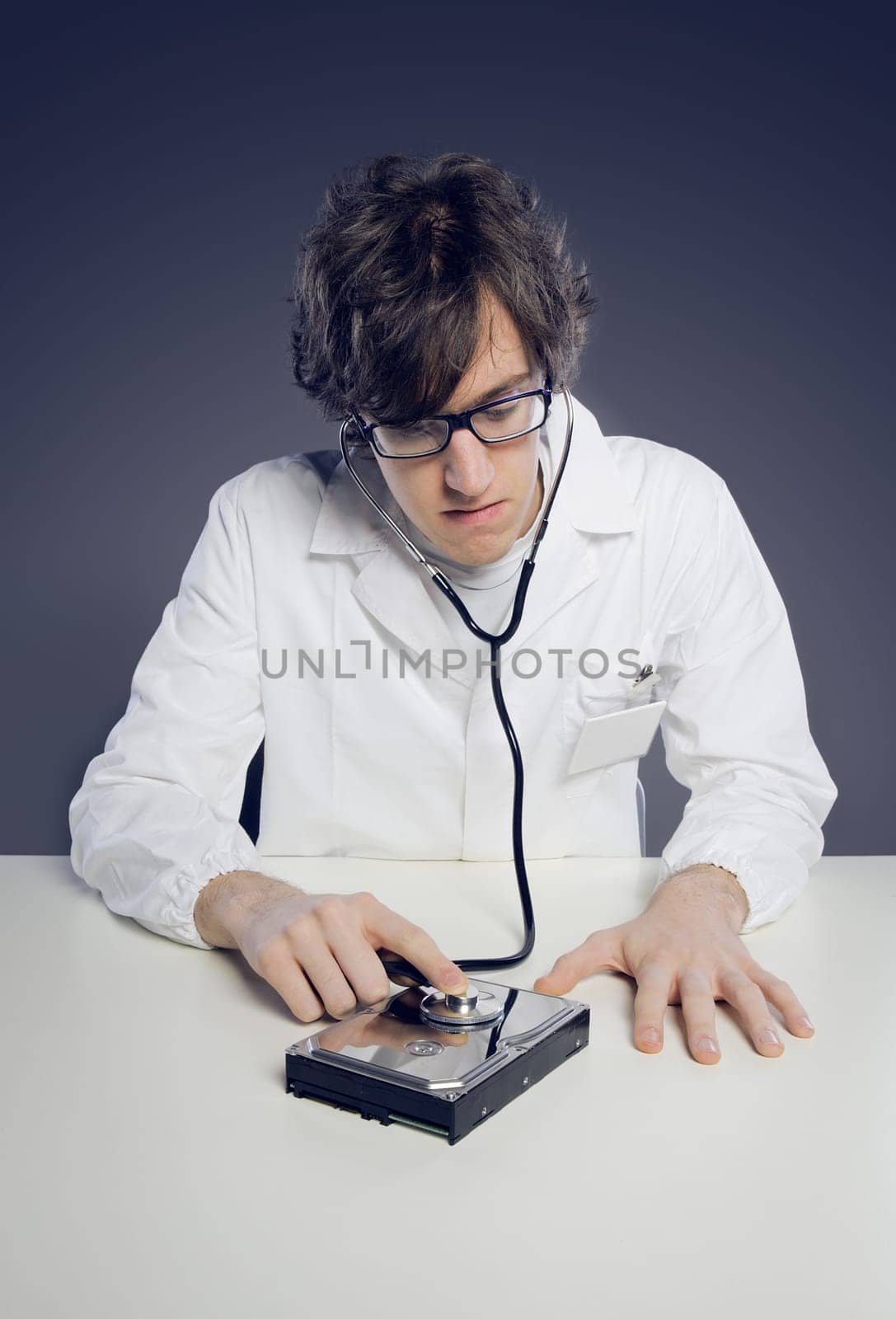 Doctor / Technician wearing a lab coat and stethoscope examining an hard disk