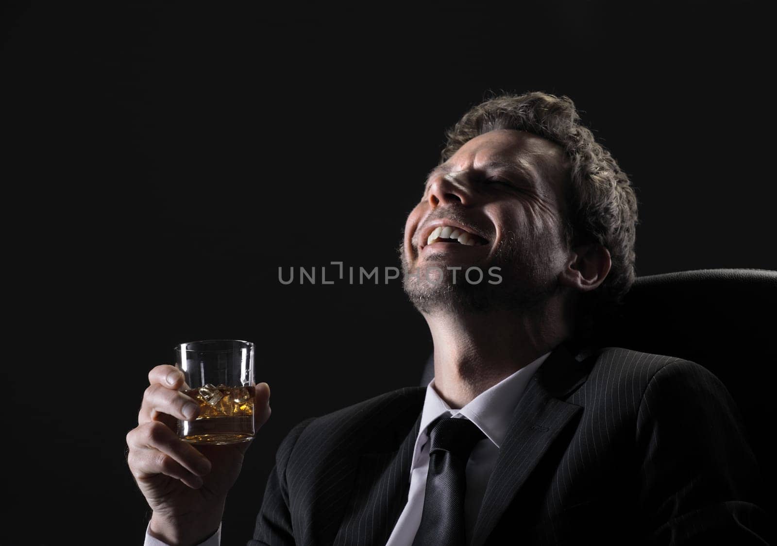 Happy middle aged man drinking whiskey against black background