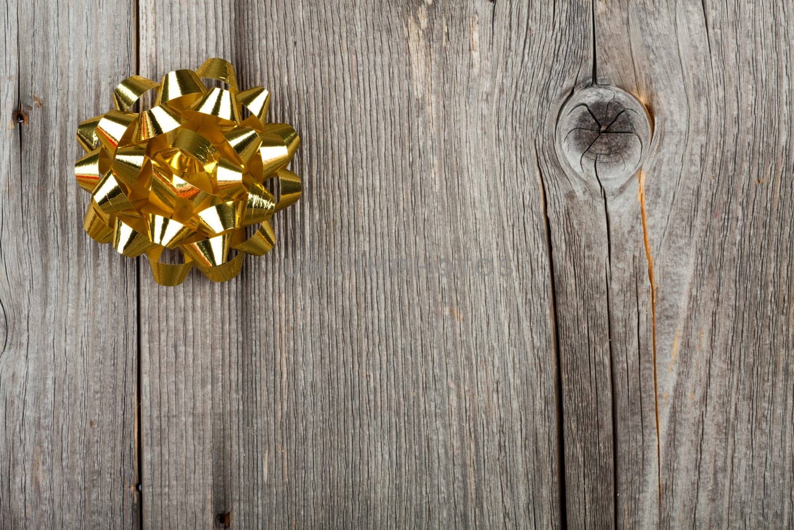 Christmas background with golden gift bow on rustic wooden background