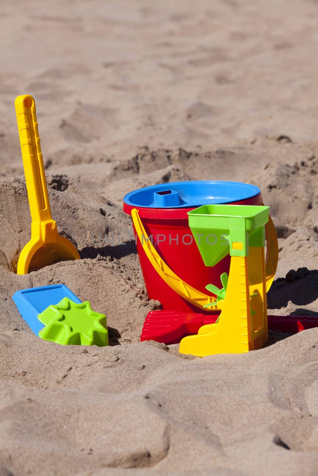 Colorful children's toys lie on the beach with text space in the upper and lower part of the picture
