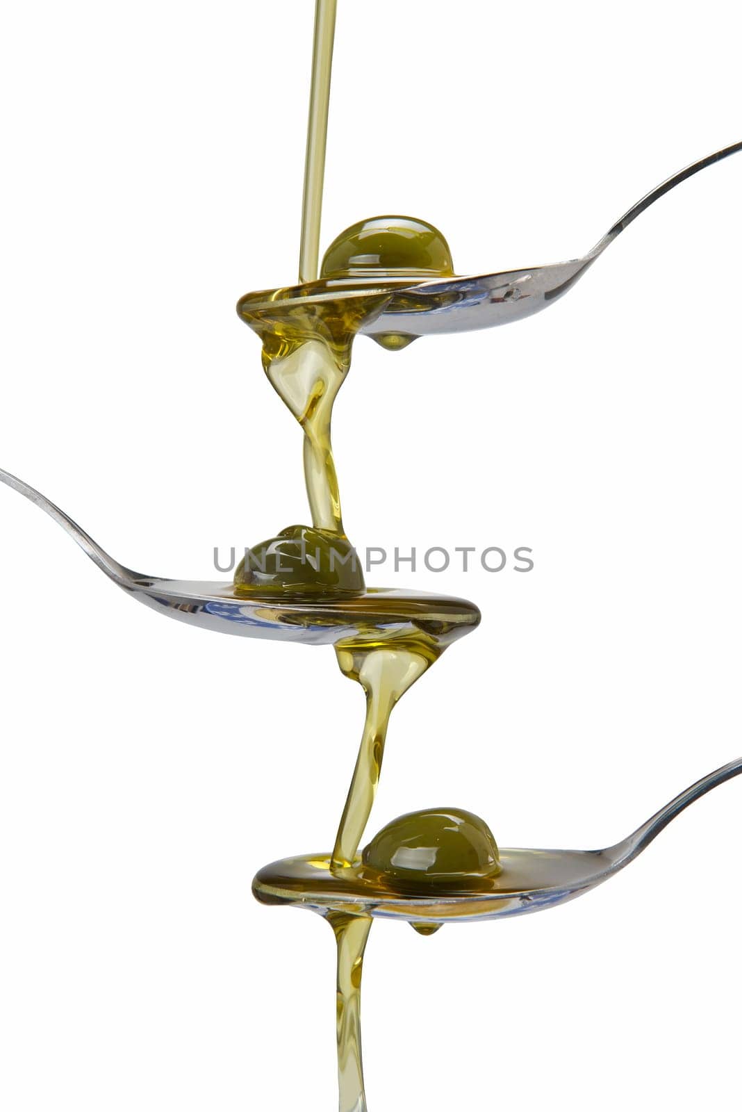 Olive oil poured into a spoon and falling from one to another spoon