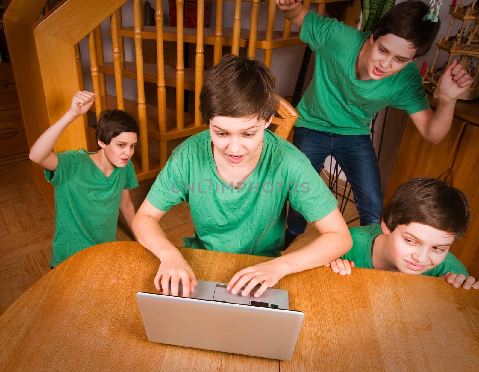 Multiple exposure of a young male teenager in a green T-shirt at the table with notebook in different poses