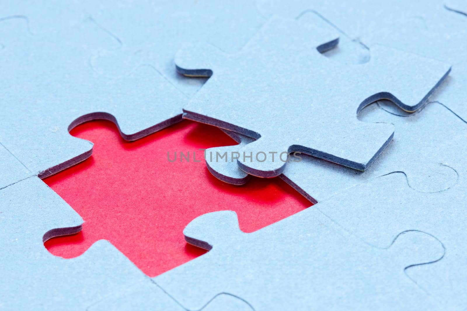 Jigsaw with one piece missing revealing red background