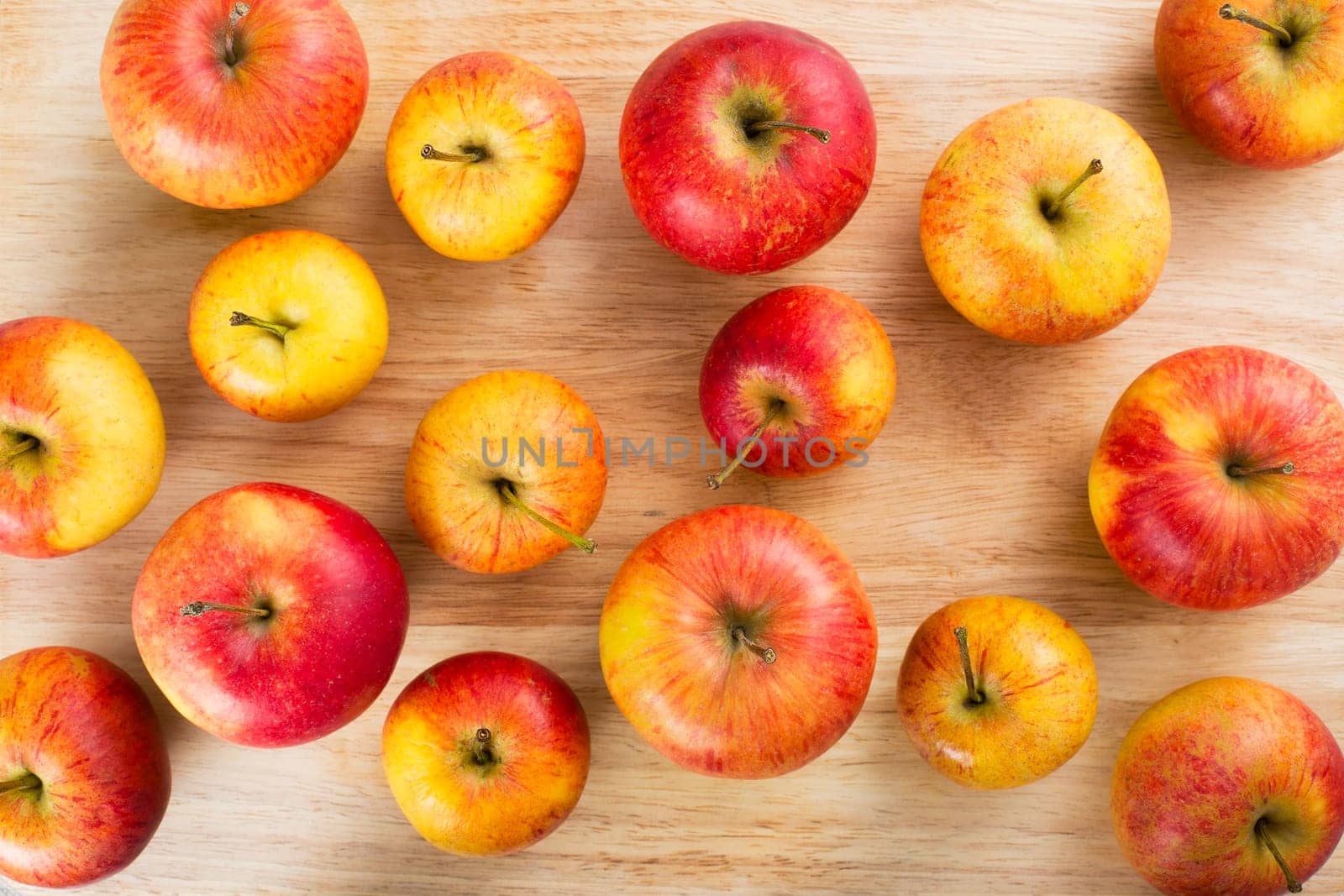Red and yellow apples on table viewed from above.