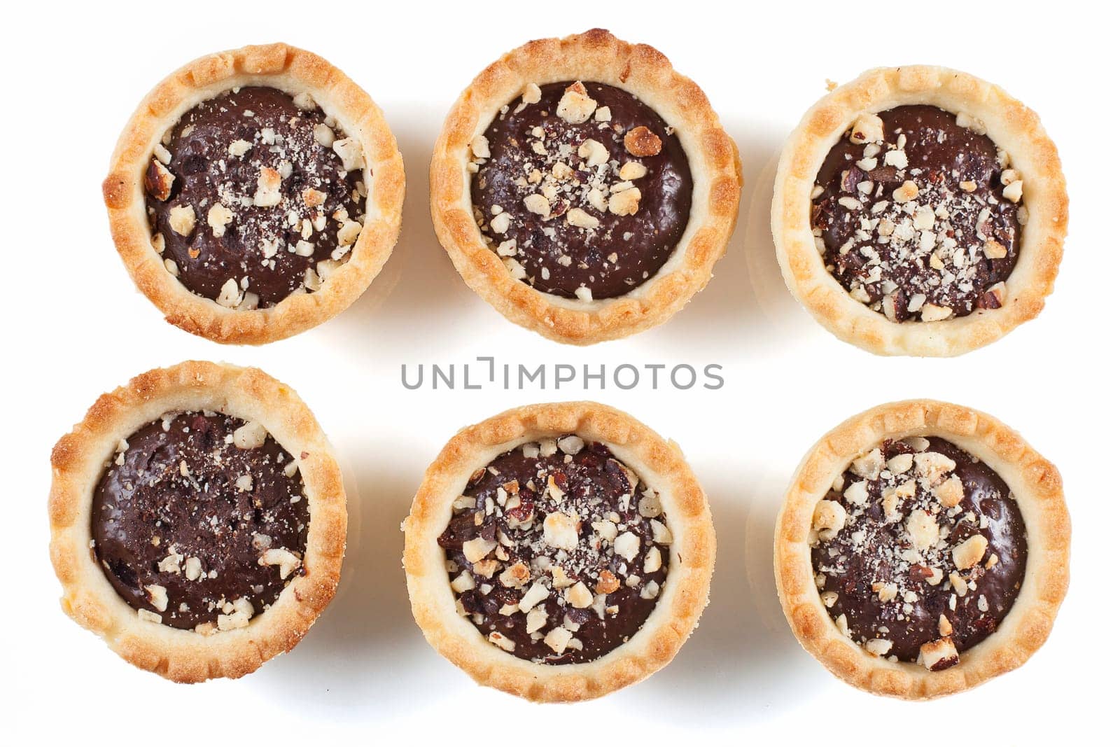 Six bite sized chocolate tarts with chopped nuts.