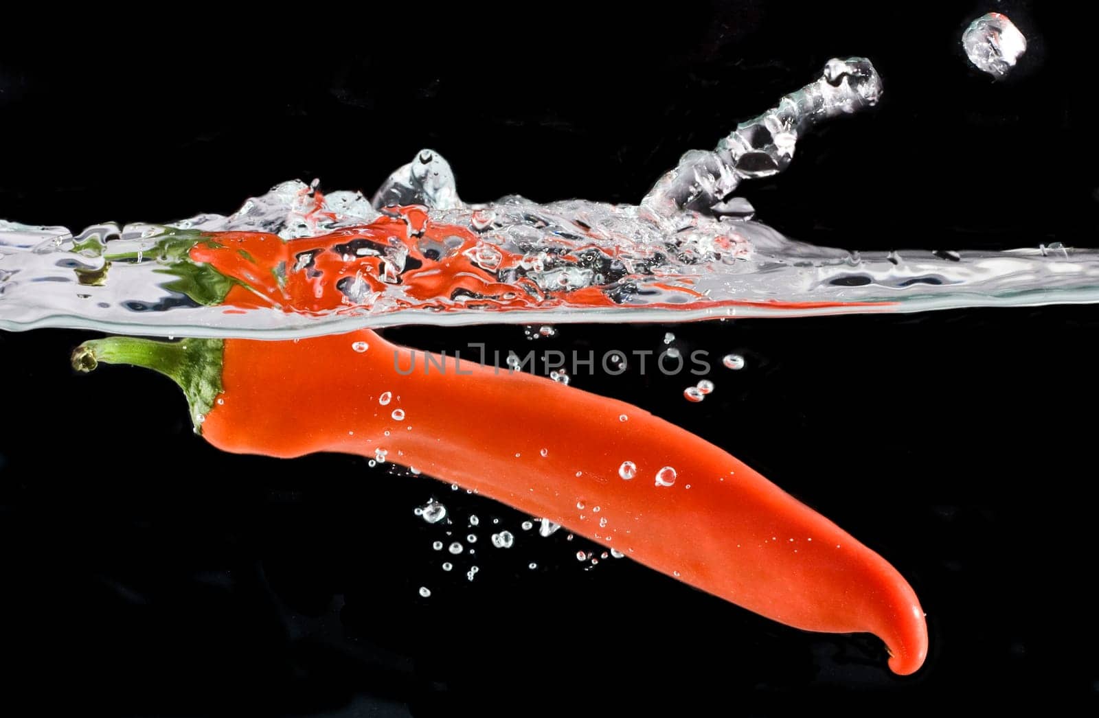 Close up on Red pepper splashing into water isolated on black