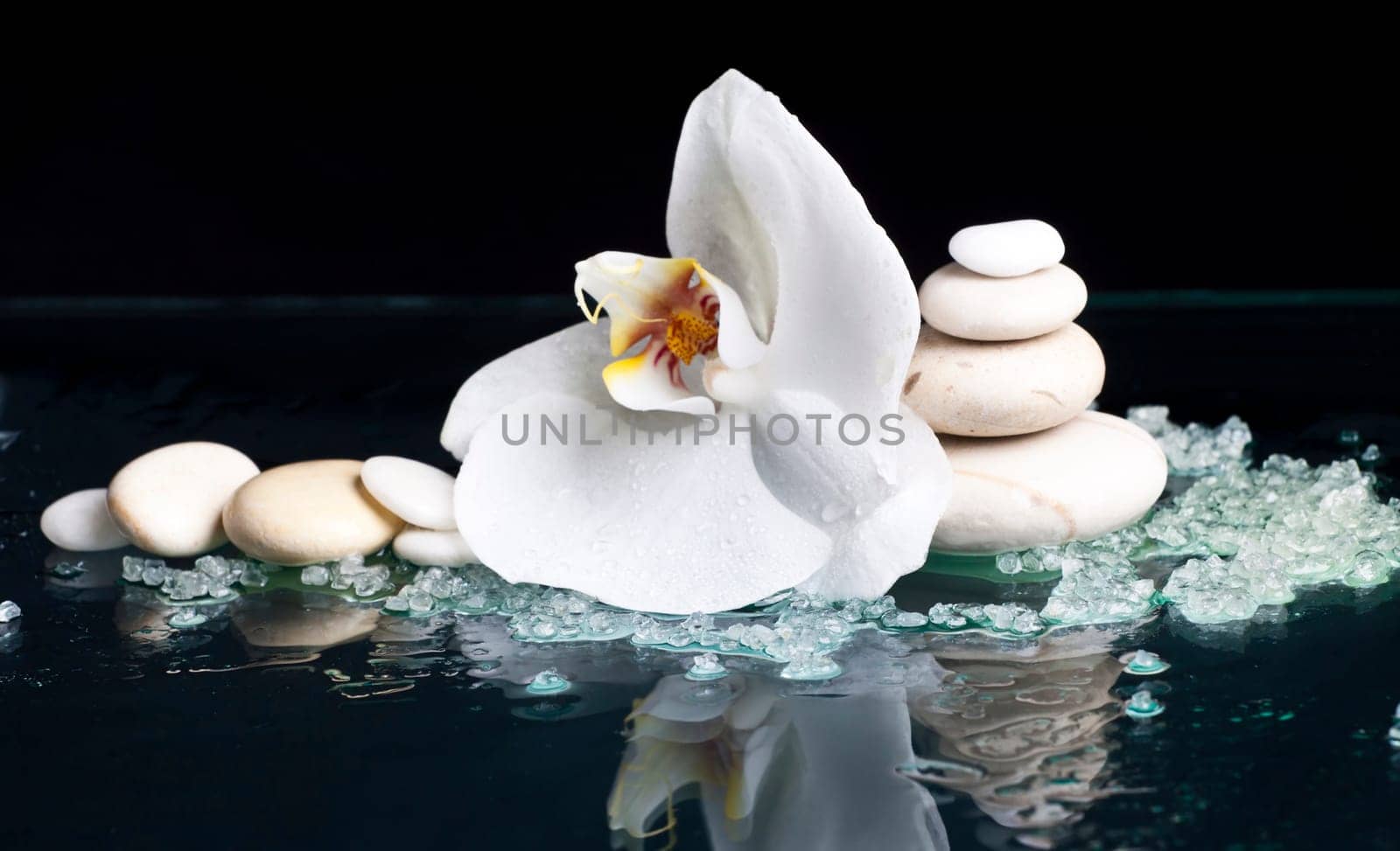 Spa stones, sea salt and with orchid flower on black background