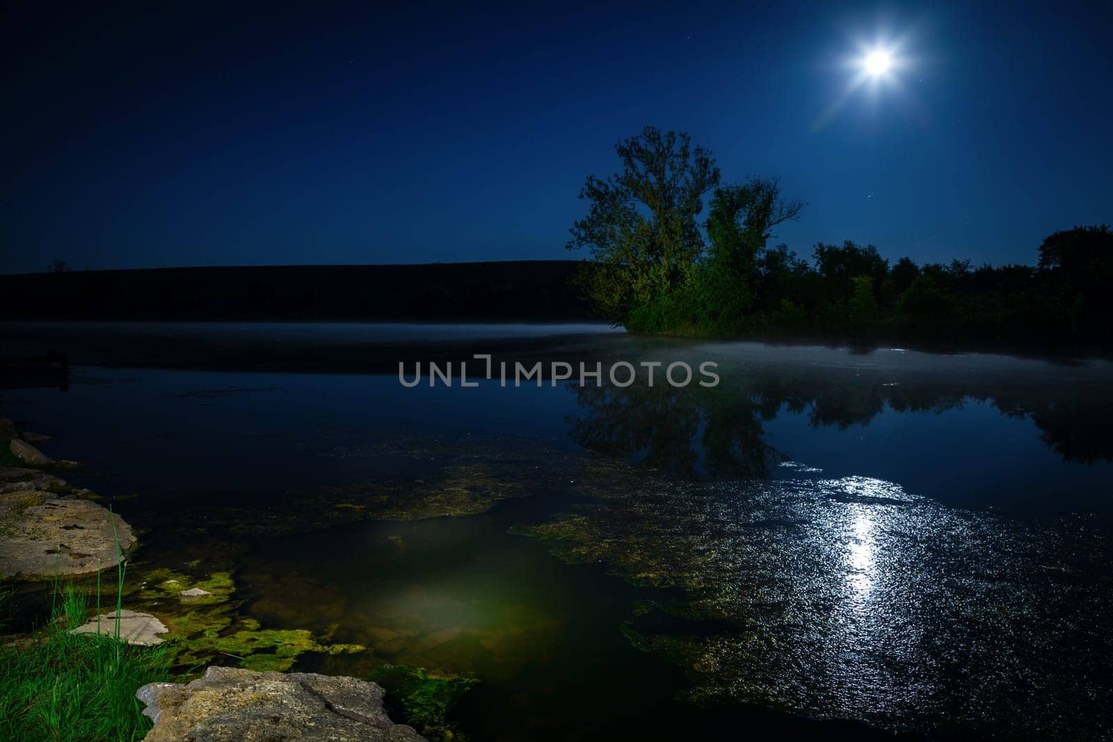 Scenic nighttime landscape with full moon rising over the lake