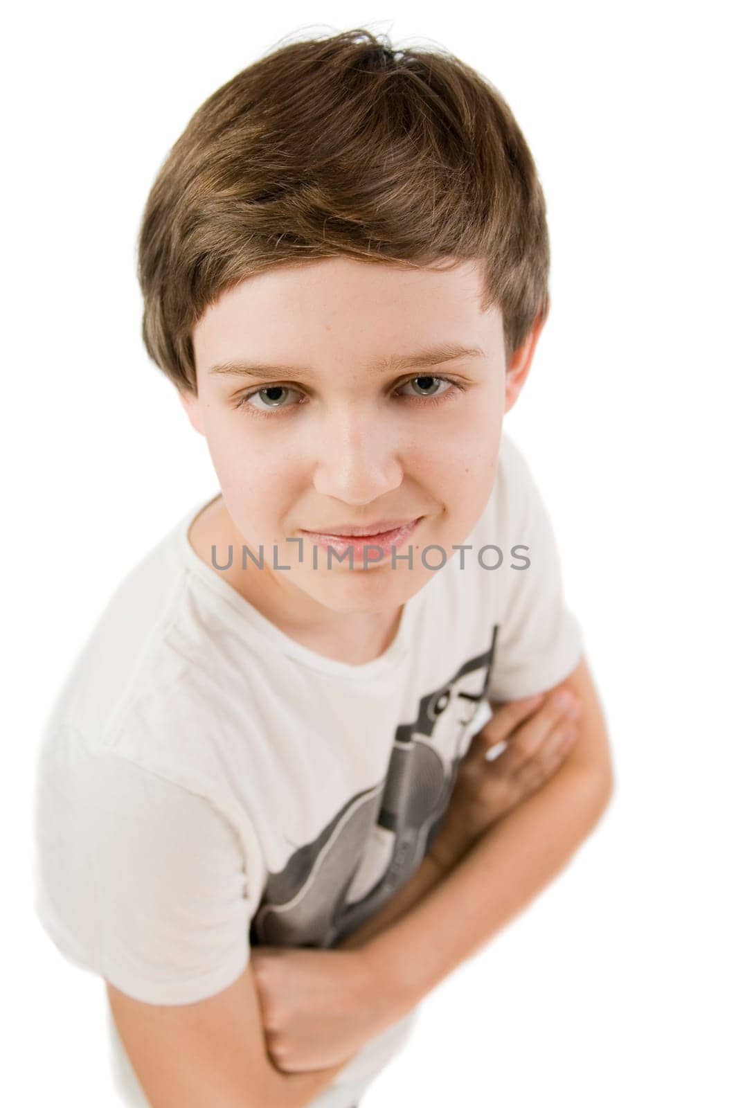 Upper body portrait of a young male teenager in a T-shirt and crossed arms in front of a white background smiling at the camera from an elevated view