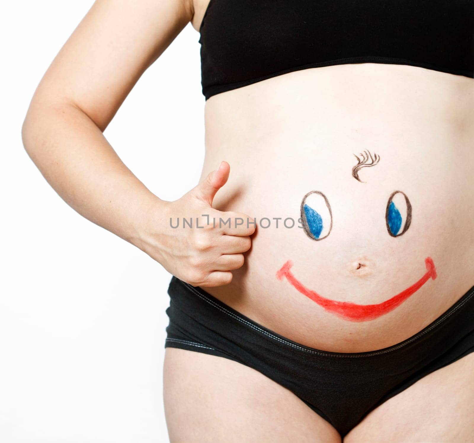 Painted happy smiley face on the belly of pregnant woman