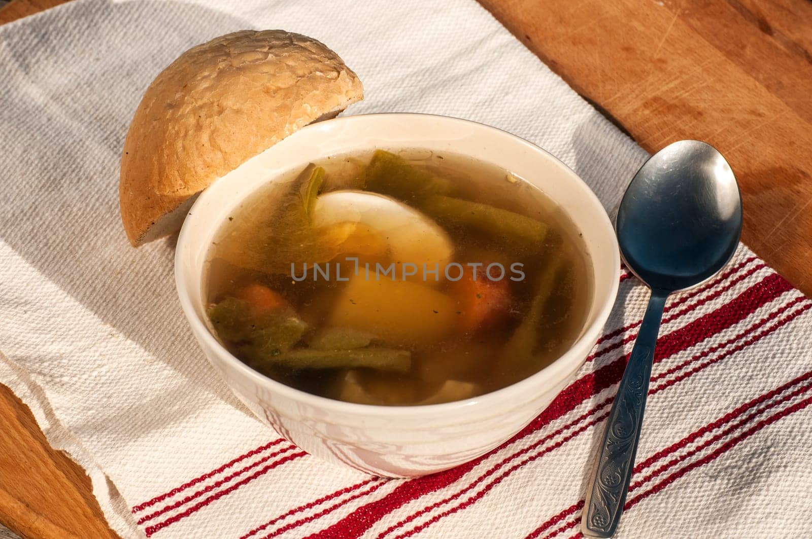 Homemade soup with meat, vegetables, boiled egg and piece of bread