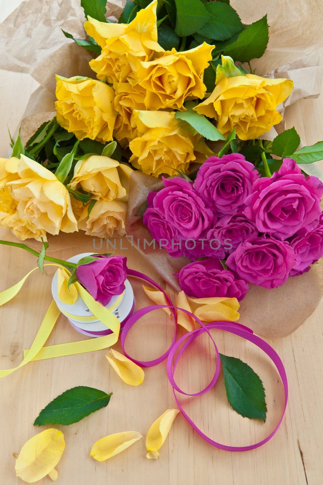 Fresh yellow and pink roses on a wooden background