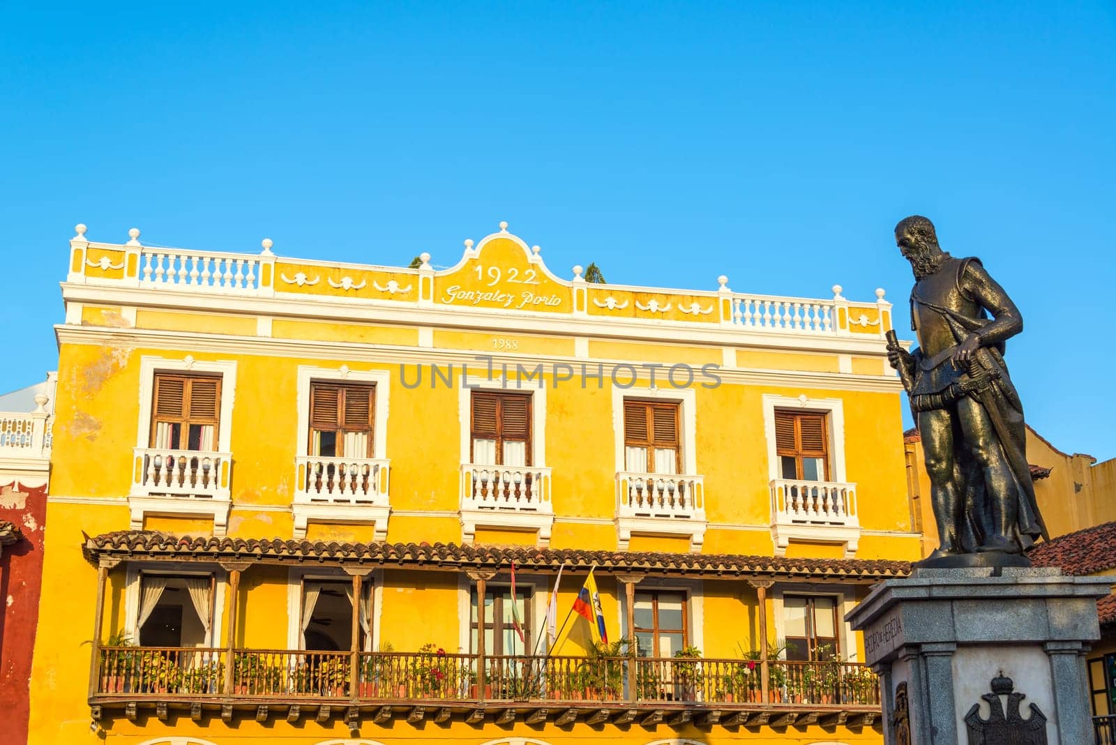 Yellow colonial building in Cartagena, Colombia with a statue of Pedro de Heredia, the founder of the city