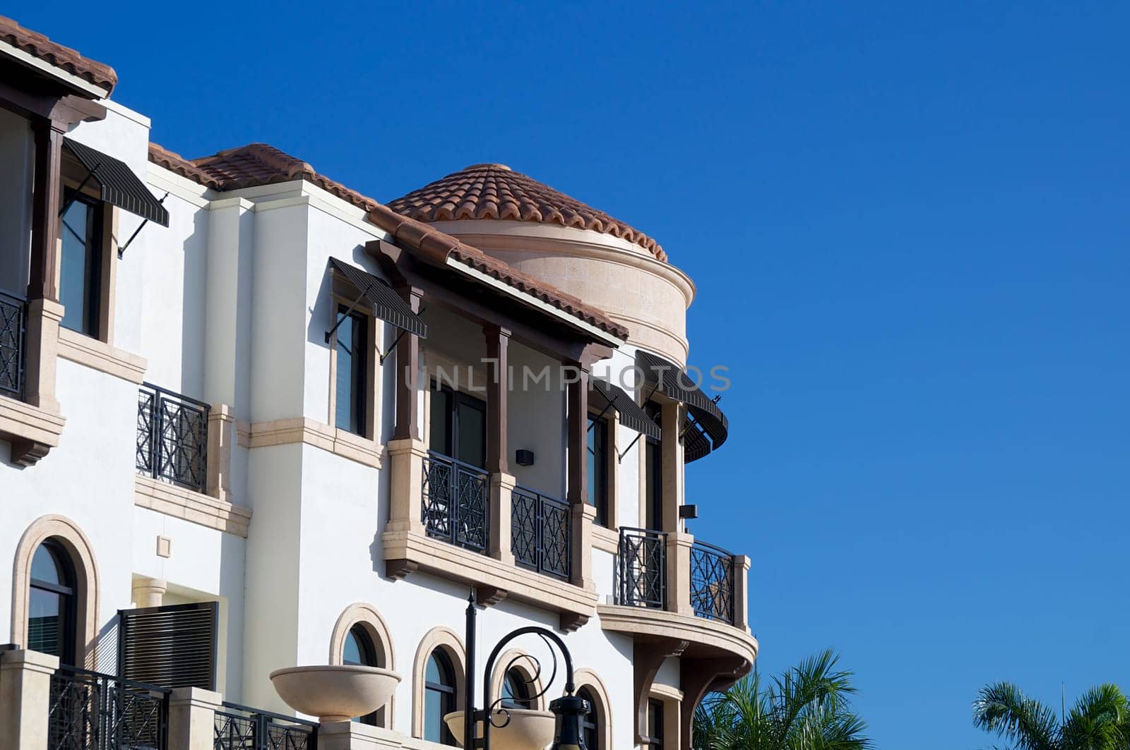 Looking up at balconies and a round room on the outside of an ornate building in tropical florida.