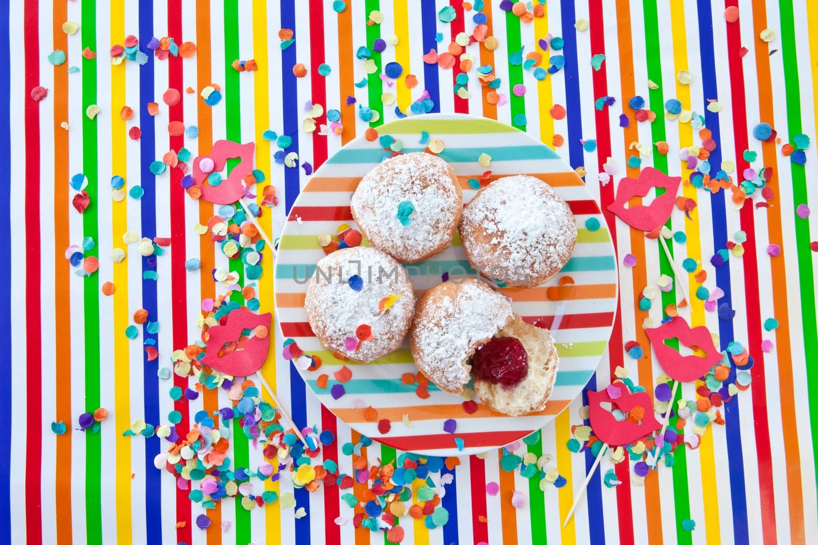 Fresh fritters on a small plate on a colorful striped background