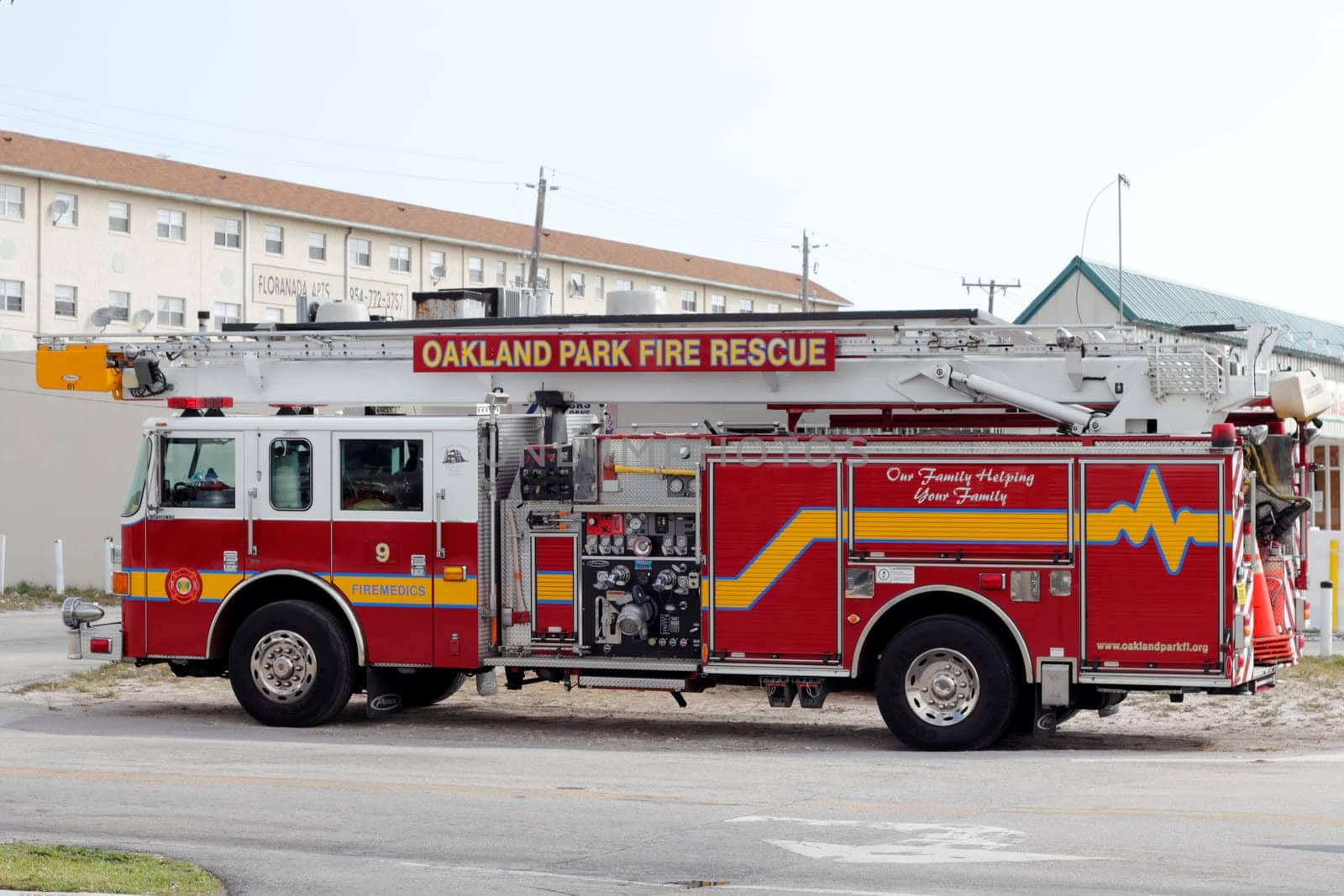 FORT LAUDERDALE, FLORIDA - FEBRUARY 13, 2013: One long Oakland Park fire rescue firemedics truck with ladder that has various signs painted onto the side of it, parked on a street near a store.