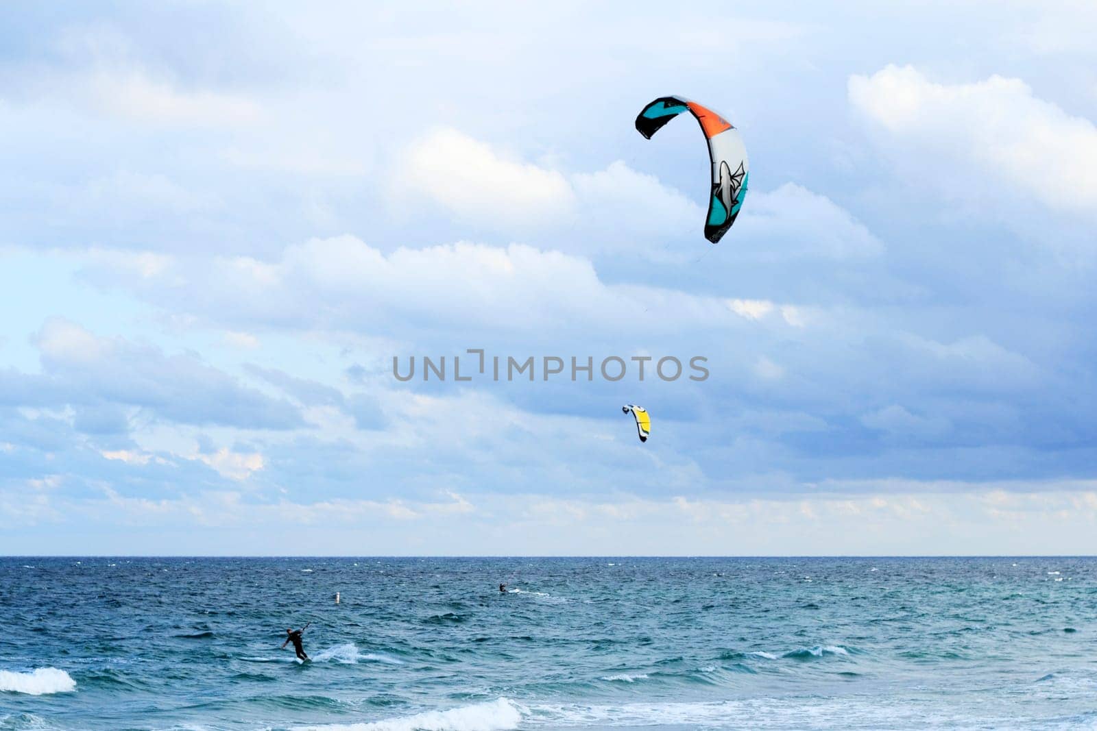 FORT LAUDERDALE, FLORIDA - FEBRUARY 9, 2013: Two kite surfers having fun kiteboarding with colorful kites on the Atlantic ocean on a windy and partly cloudy day winter morning.