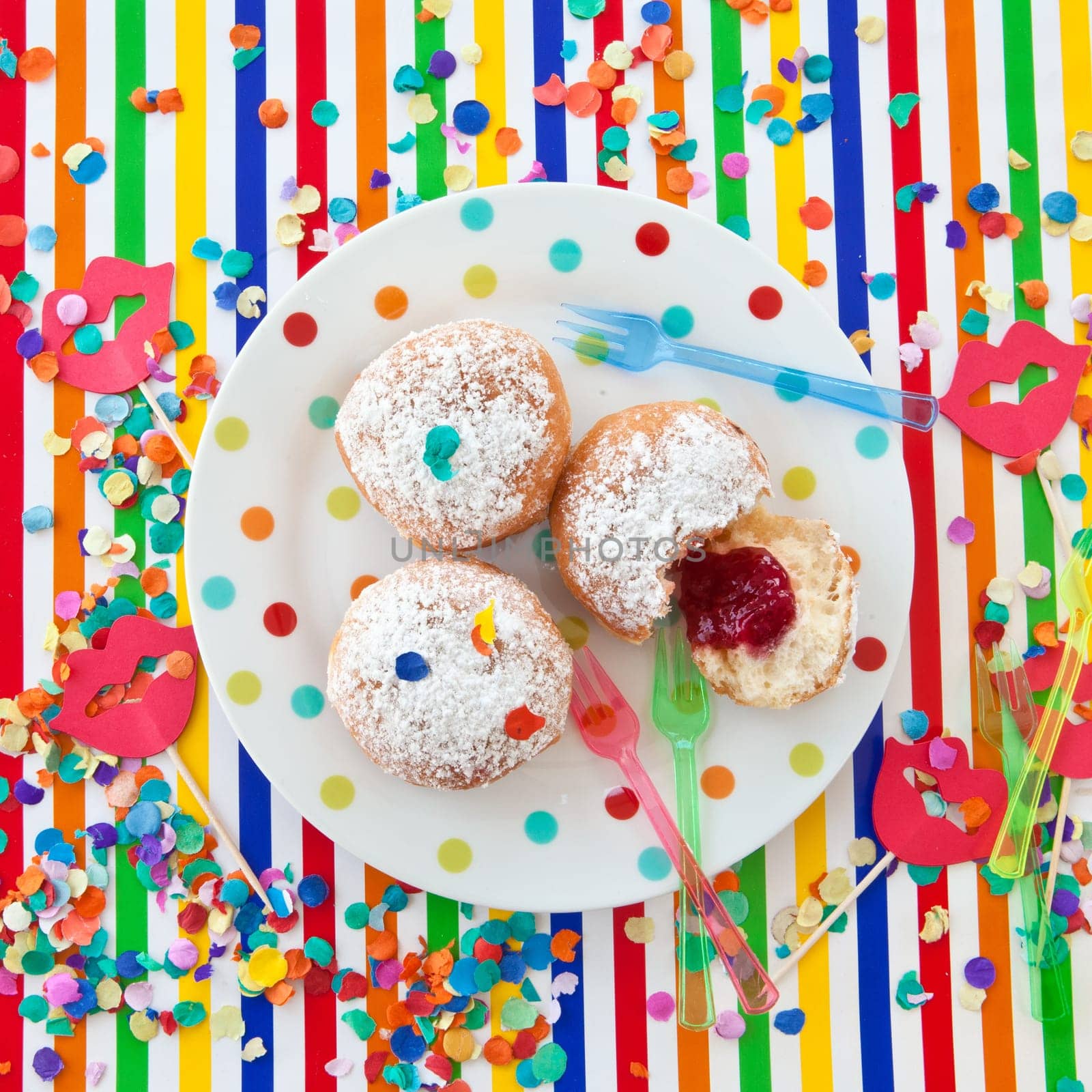 Fresh fritters on a small plate on a colorful striped background