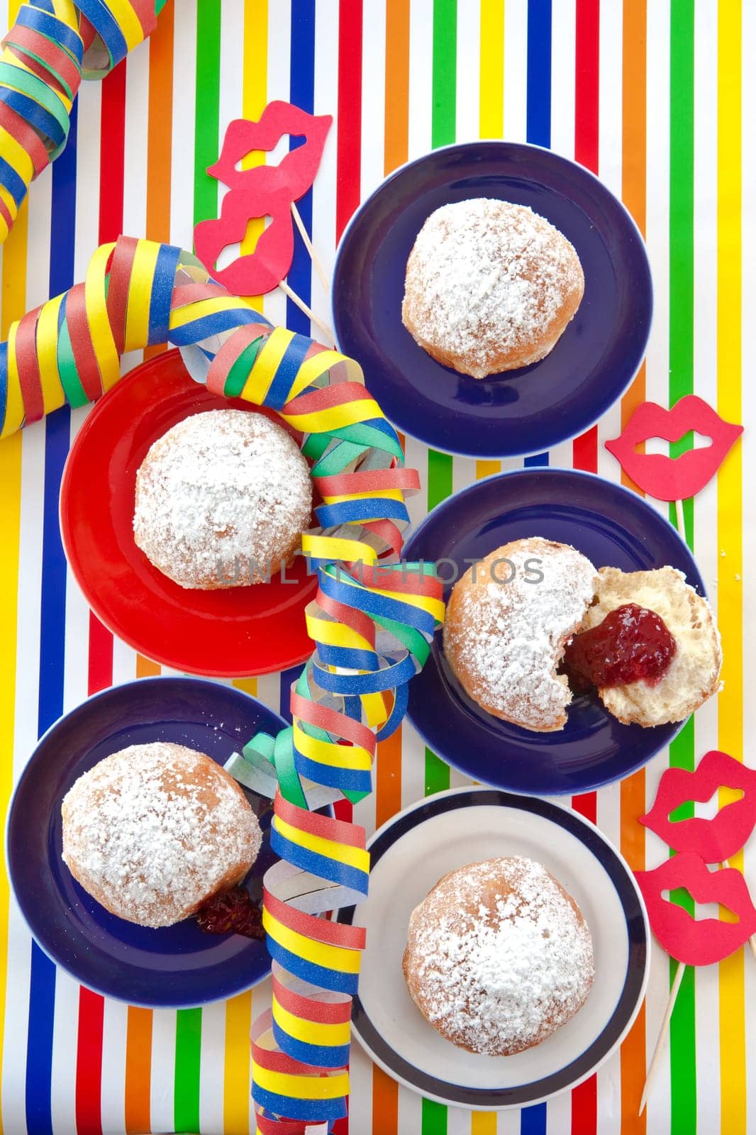 Fresh fritters on small plates on a colorful striped background