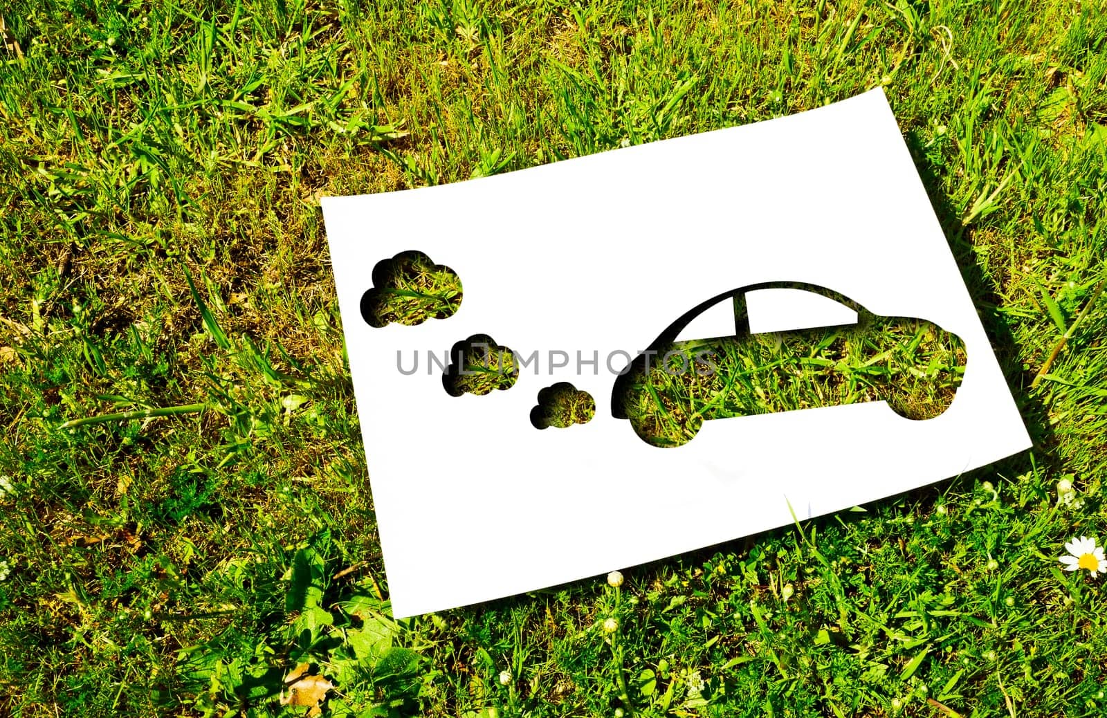 White paper cut in the shape of a car on a background of grass. Renewable energy concept
