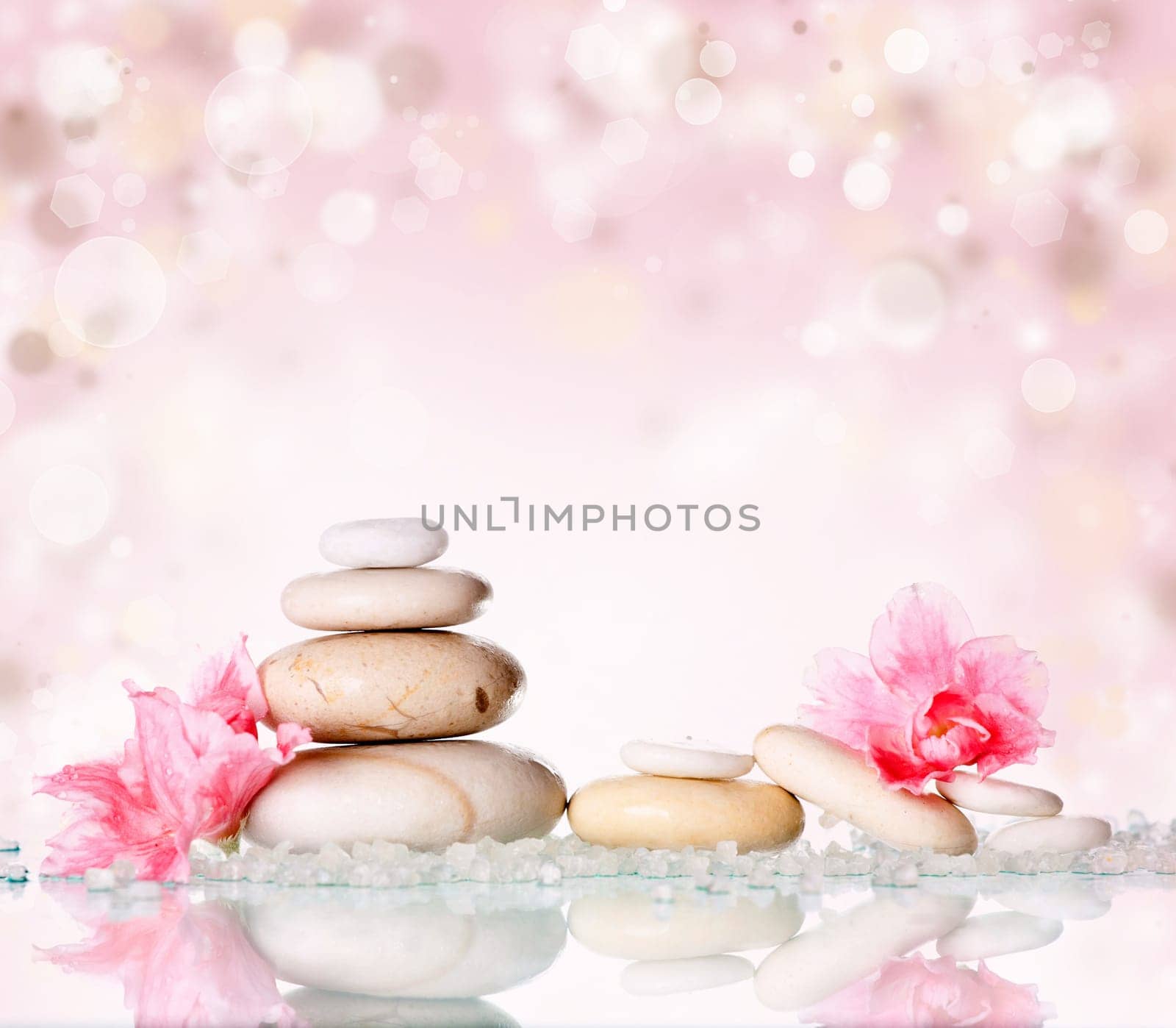 Spa stones and pink flower on abstract pink background