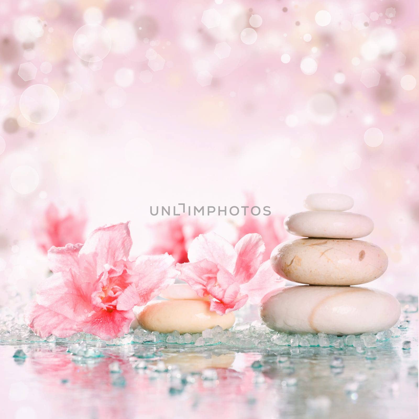 Spa stones and pink flower on abstract pink background