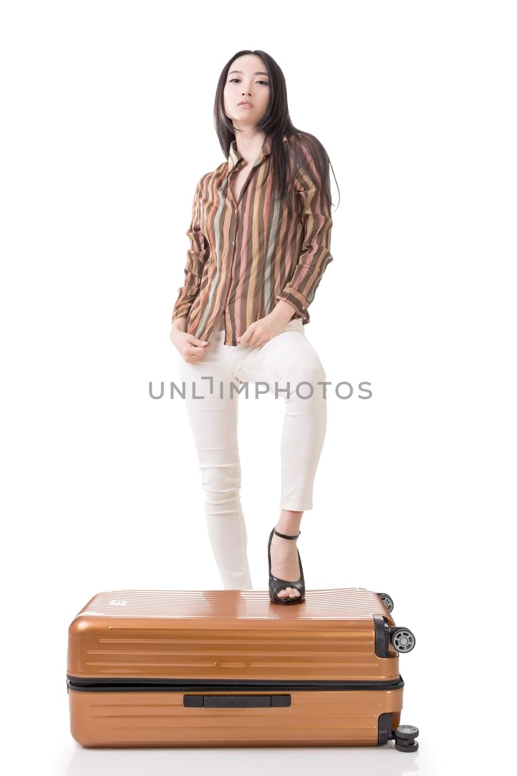 Modern Asian woman stand on a luggage, full length portrait on white background.