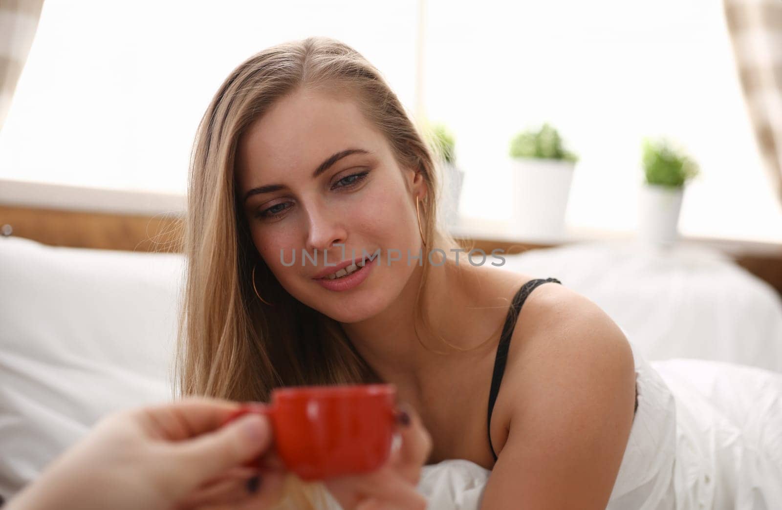Beloved husband brings early morning coffee to bed for young pretty blond woman have cup of tea coffee early morning in her bed