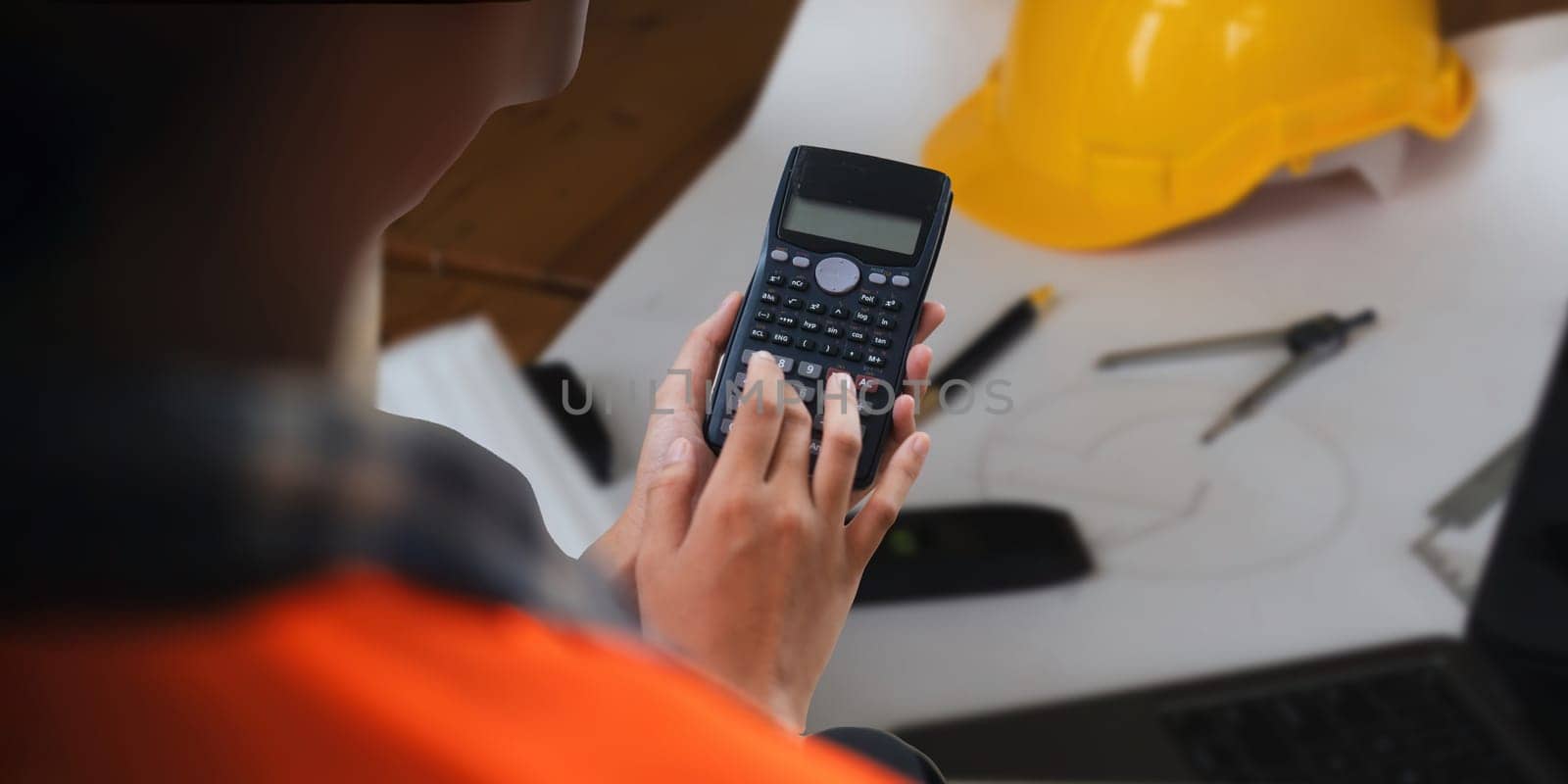 Closeup hand of engineer with construction work plan together blueprint on working table in construction site with safety helmet.