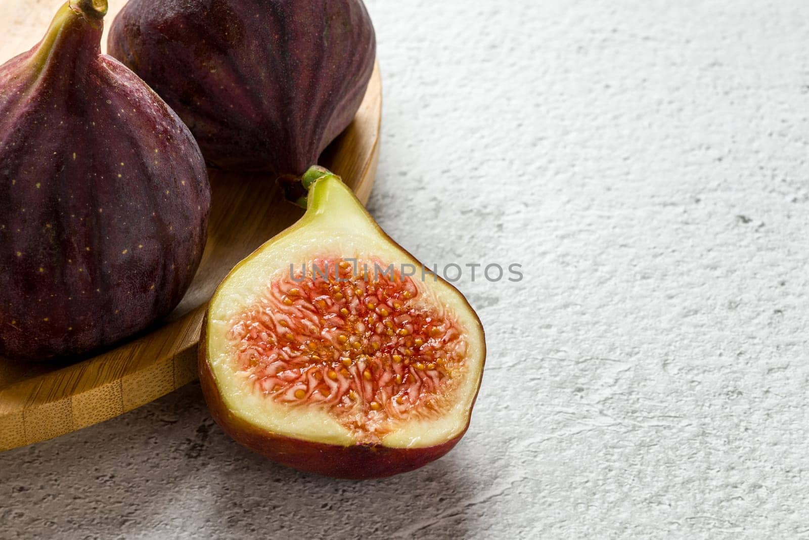 View of whole and cut organic figs on stone table